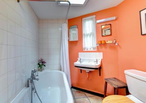 baño de color naranja con bañera y lavamanos en 6 Coastguard Cottages en Hollesley