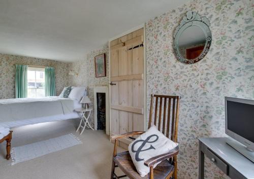 um quarto com uma cama, uma televisão e um espelho em 9 Gate Cottage em Long Melford