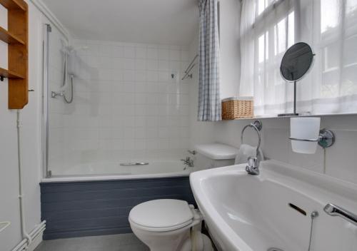 a bathroom with a toilet and a tub and a sink at 9 Gate Cottage in Long Melford