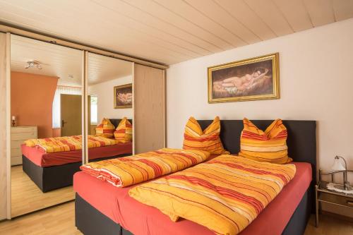 テュービンゲンにあるFerienwohnung Schmidのベッドルーム1室(オレンジと黄色の枕を使用したベッド2台付)