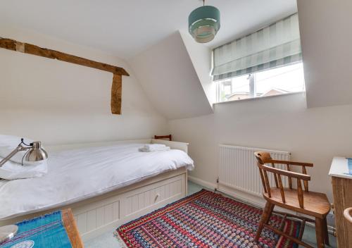 a bedroom with a bed and a chair and a window at Anchor Cottage in Woodbridge