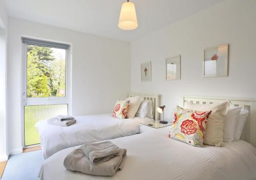 two beds in a white room with a window at Arva in Southwold