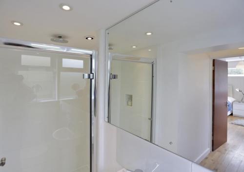 a glass shower in a bathroom with a mirror at Arva in Southwold