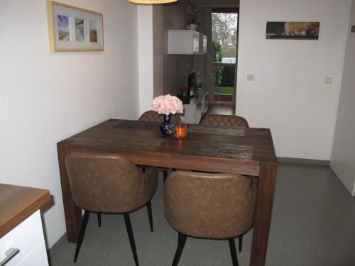 uma mesa de madeira com cadeiras e um vaso de flores em Holiday Home Strandvilla - LUB117 by Interhome em Lubmin