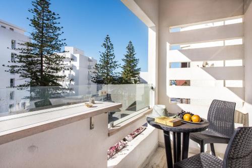 d'un balcon avec une table, des chaises et une grande fenêtre. dans l'établissement Sea Star Apartments - Casa Verde e Casa Azul, à Armação de Pêra
