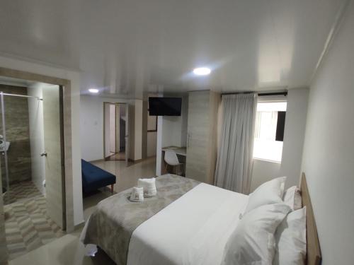 a bedroom with a large white bed and a television at Hotel Meraki Popayán in Popayan