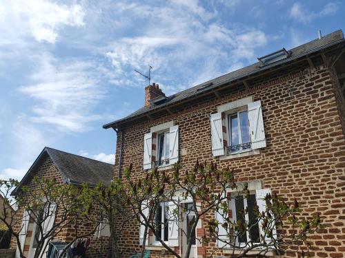 une maison en briques avec des fenêtres blanches et un arbre dans l'établissement Chambre double 24 heures, à Laigné-en-Belin