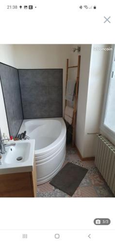 La salle de bains est pourvue d'une baignoire blanche et d'un lavabo. dans l'établissement Chambre double 24 heures, à Laigné-en-Belin