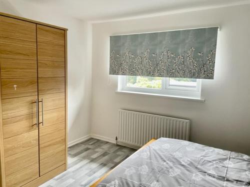 1 dormitorio con cama y ventana con cortina en Fabulous, Spacious, Newly Refurbished Home close to Heathrow Airport en Hayes