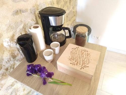 a wooden cutting board with a coffee maker and purple flowers at Sous un chêne bicentenaire agréable Chambre avec jardin et espace de W in Lambesc