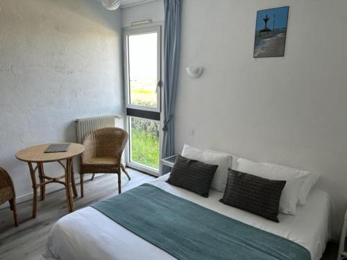 een slaapkamer met een bed, een tafel en een raam bij Hotel Les Esseppes in LʼÉpine