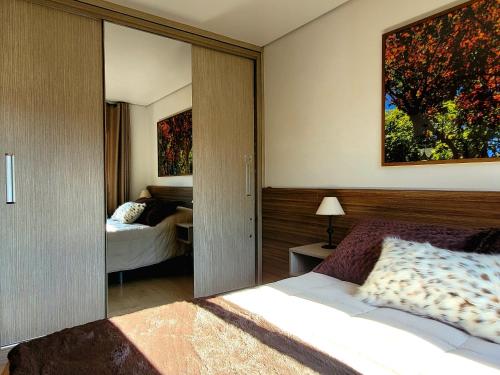 a bedroom with a bed and a large mirror at Solar da Encosta 305 - Espaço e conforto no Centro in Gramado