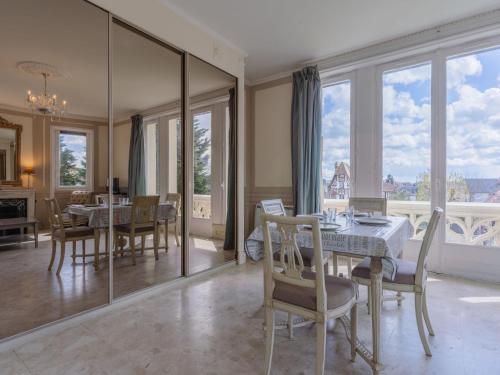 comedor con mesa, sillas y ventanas en Apartment Marie Antoinette-1 by Interhome, en Cabourg