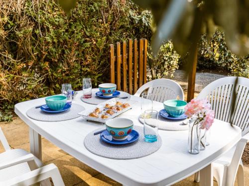 une table blanche avec des assiettes de nourriture et des tasses dessus dans l'établissement Holiday Home Hameau de Talaris-4 by Interhome, à La Palmyre