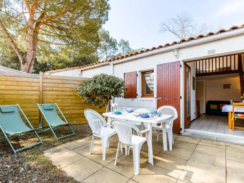 een patio met een tafel en stoelen en een hek bij Holiday Home Hameau de Talaris-4 by Interhome in La Palmyre