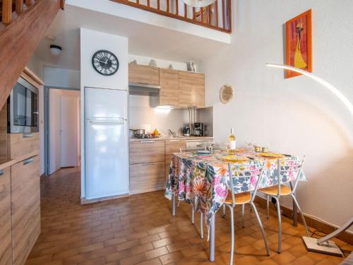 a kitchen with a table and a clock on the wall at Holiday Home Les Maisons de la Plage-7 by Interhome in Le Grau-du-Roi