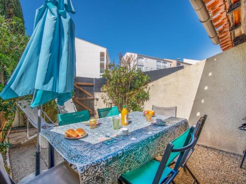 - une table avec des chaises et un parasol sur le balcon dans l'établissement Holiday Home Les Maisons de la Plage-7 by Interhome, au Grau-du-Roi