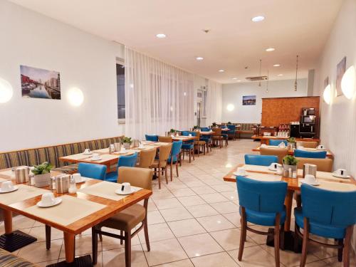 Trip Inn Hotel Minerva Frankfurt في فرانكفورت ماين: مطعم بطاولات خشبية وكراسي زرقاء