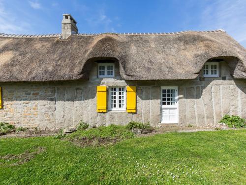 an old stone house with a thatched roof at Holiday Home Chaumiere Natelliou by Interhome in Trégunc