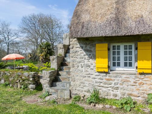 an old stone house with yellow doors and a thatched roof at Holiday Home Chaumiere Natelliou by Interhome in Trégunc