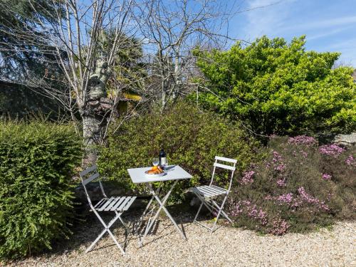 a table and two chairs in a garden at Holiday Home Chaumiere Natelliou by Interhome in Trégunc