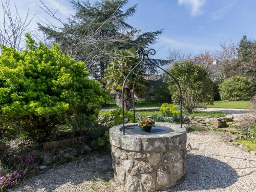 a garden with a stone fountain in a yard at Holiday Home Chaumiere Natelliou by Interhome in Trégunc