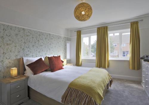 a bedroom with a large bed and two windows at Bon Amis in Southwold