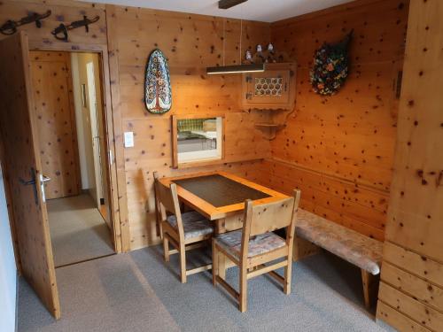 ダボスにあるApartment Guardaval - Utoring-33 by Interhomeの木製の壁の客室で、テーブルと椅子が備わります。