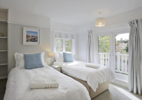 a white bedroom with two beds and a window at Braeside House in Reydon