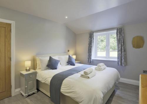 a bedroom with a large bed with towels on it at Bluebell Cottage in Beccles
