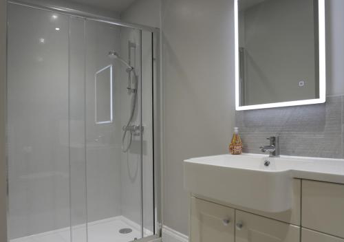 a bathroom with a shower and a sink and a mirror at Bluebell Cottage in Beccles