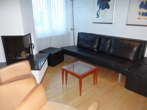 salon z czarną skórzaną kanapą i stolikiem kawowym w obiekcie Apartment Dorfstrasse 15 by Interhome w mieście Engelberg