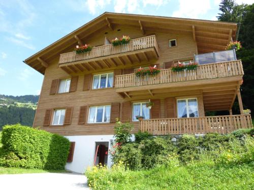 ein großes Holzhaus mit Blumen auf dem Balkon in der Unterkunft Apartment Berg by Interhome in Engelberg