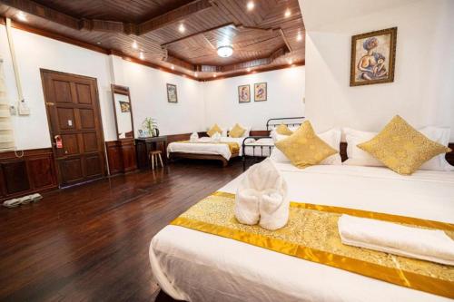 a hotel room with two beds and a living room at Mekong Chidlatda Villa in Luang Prabang