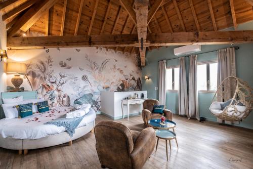 a bedroom with a bed and chairs in a room at Le Belvédère Hotel et Bien être in Lauzerte