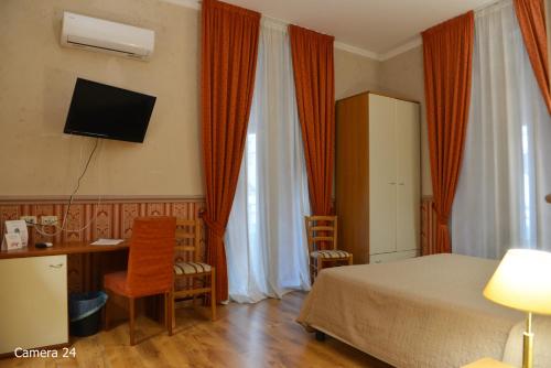 een slaapkamer met een bed, een bureau en een televisie bij Catania Centro Rooms in Catania