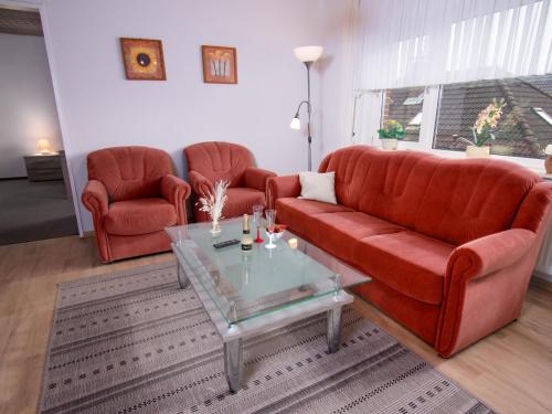 ein Wohnzimmer mit einem roten Sofa und einem Tisch in der Unterkunft Apartment Lachmöwe by Interhome in Norddeich