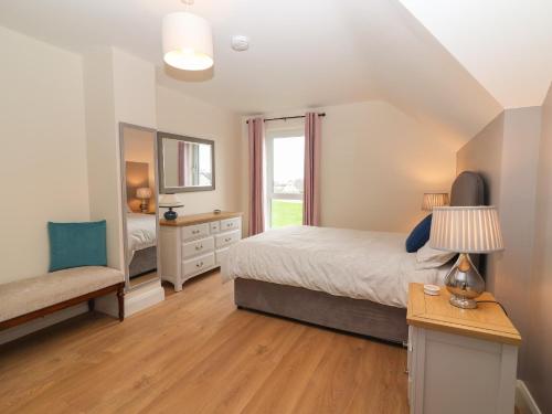 a bedroom with a bed and a chair and a window at 20 Lighthouse Village in Fenit