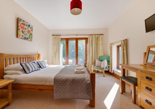 a bedroom with a bed and a desk and window at Buttercup Lodge in Darsham