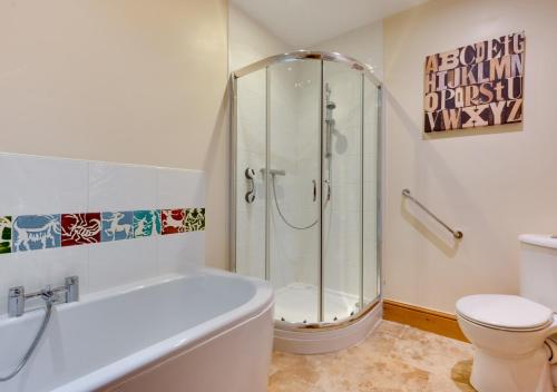 ein Badezimmer mit einer Dusche, einer Badewanne und einem WC in der Unterkunft Buttercup Lodge in Darsham