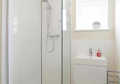 a shower with a glass door next to a sink at Camomile Cottage in Friston