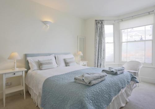 a white bedroom with a bed with towels on it at Caithness House in Southwold