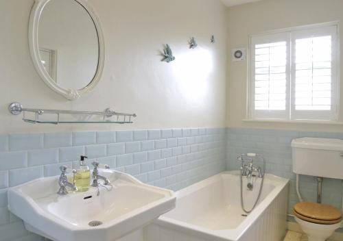 y baño con lavabo, bañera y espejo. en Caithness House, en Southwold