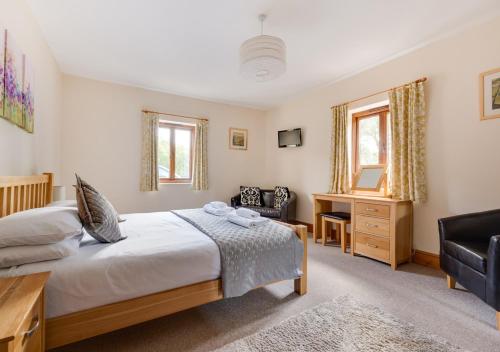 a bedroom with a bed and a desk and a chair at Canola Lodge in Darsham