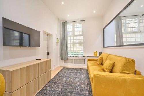 Il comprend un salon doté d'un canapé jaune et d'une télévision à écran plat. dans l'établissement Marais - Modern apartment, à Paris