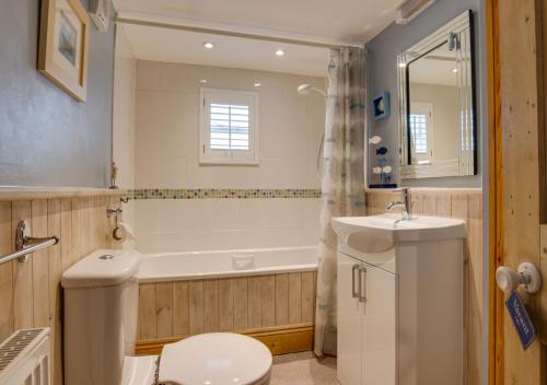 a bathroom with a toilet and a sink and a tub at Church Cottage in Wangford