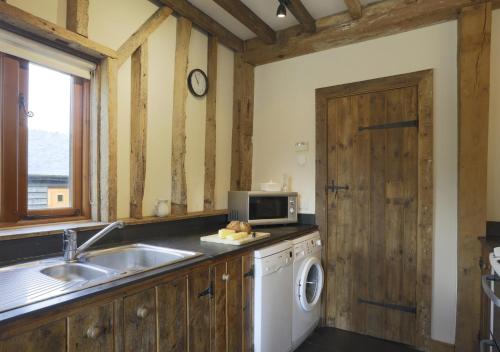 a kitchen with a sink and a washing machine at Christmas Cottage Sternfield in Friston