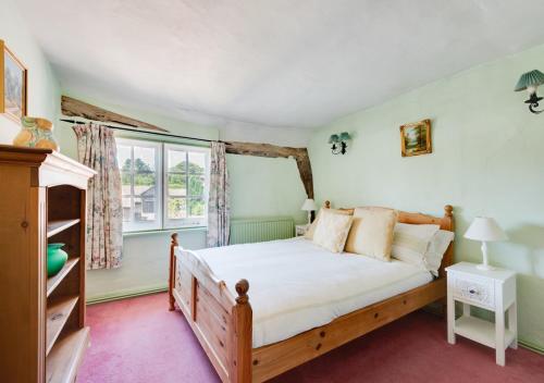 a bedroom with a bed and a window at Clematis Cottage in Lavenham