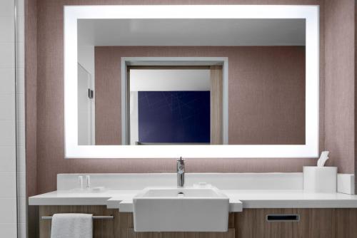 SpringHill Suites Winchester في وينشستر: حمام مع حوض ومرآة كبيرة
