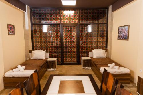 a room with two beds and a table and chairs at Qala Hostel Ganja in Ganja